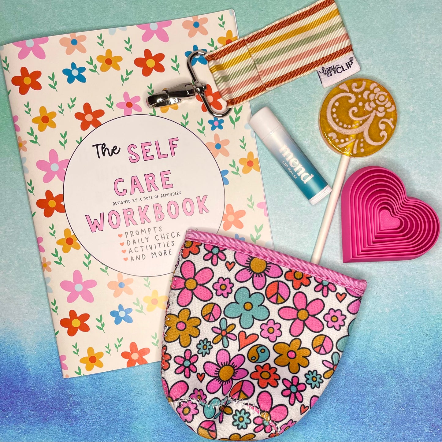 Spring Millions of Peaches Box featuring a self care workbook from A Dose of Reminders, Mend Lip Balm and a Lippy Clip to keep it handy, heart shaped fidget toy from Lauren Ann Designs, a mango flavored lollipop, and a coffee cozy from Elle Nicole